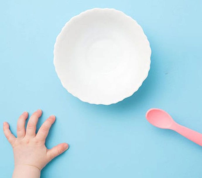 Manita de un niño frente a un plato vacío